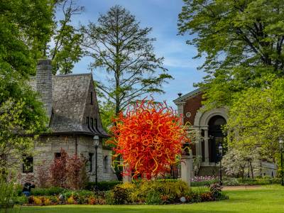 Chihuly - An orange venetian glass sculpture in a garden by a stone house