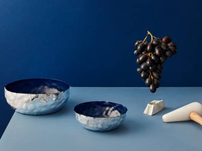 Jordan Keaney - metal bowls and floating grapes on a light blue table in front of a dark blue wall
