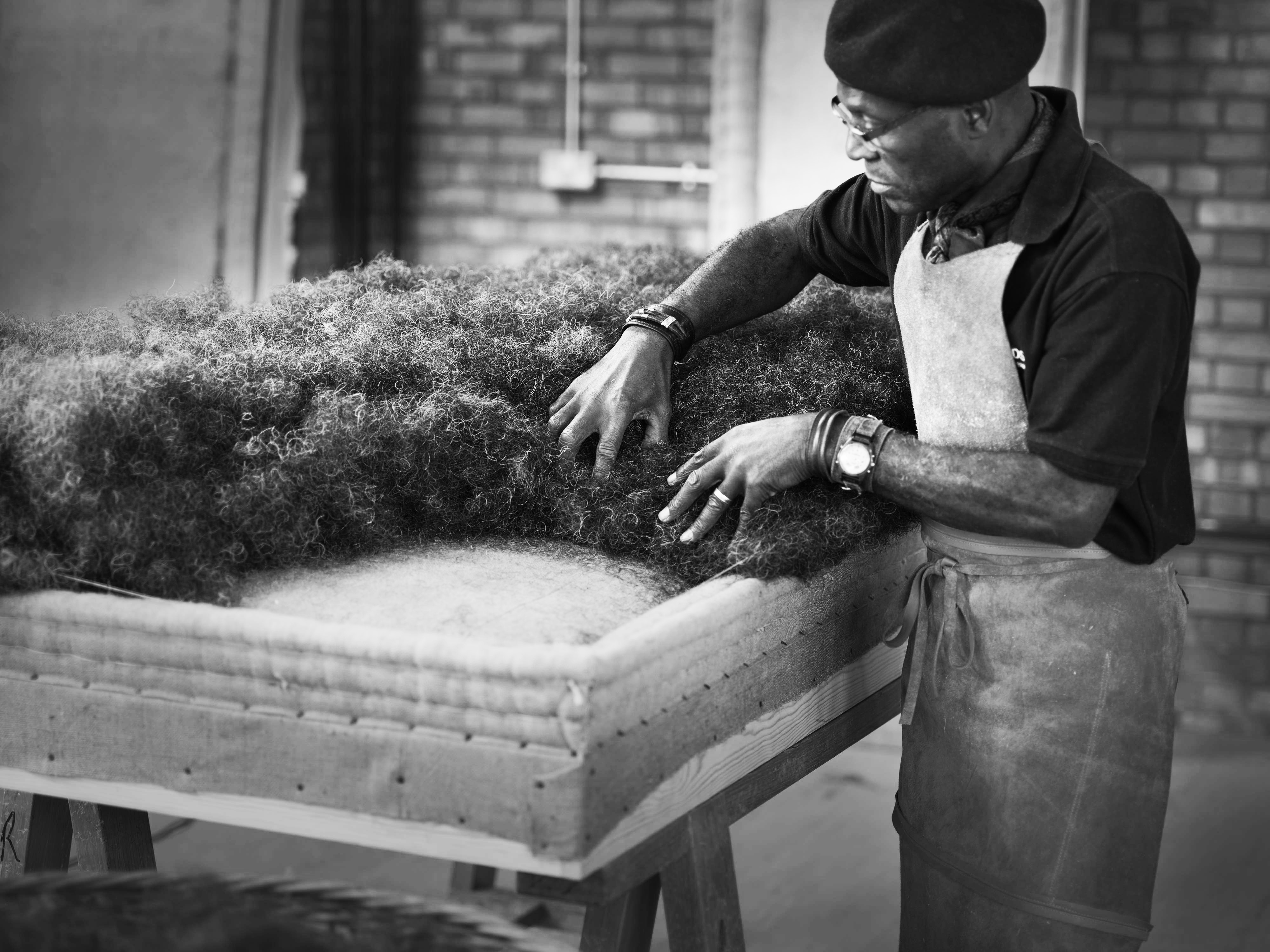 A craftsman adds layers of natural fibres such as wool to the mattress A craftsman adds layers of natural fibres such as wool to the mattress