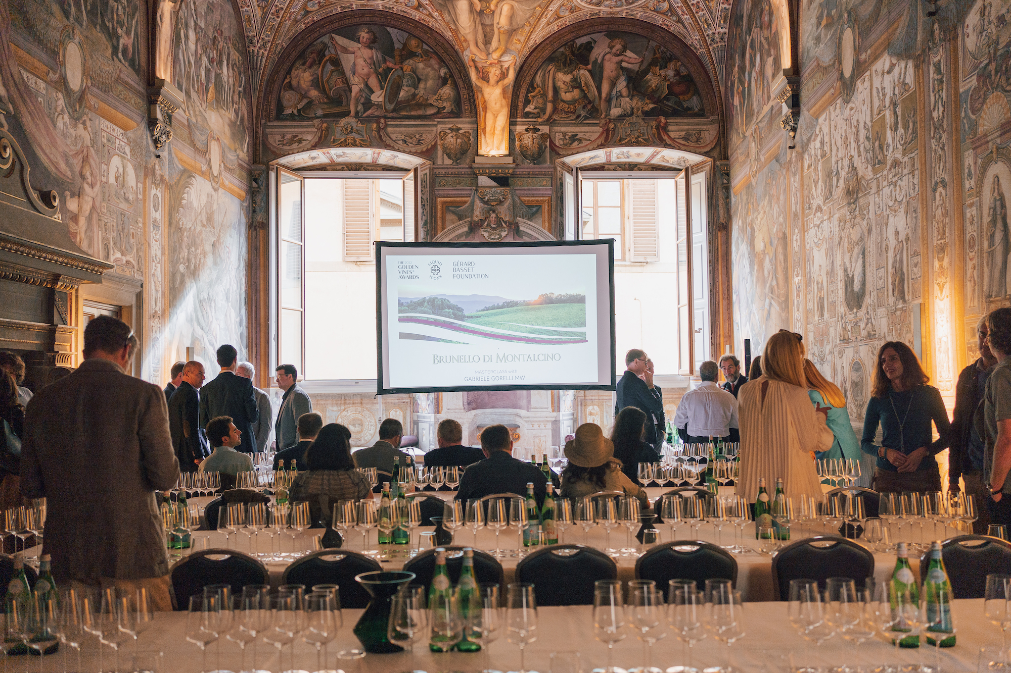 Golden Vines - Masterclass Golden Vines -people in a grand italian room looking at a screen with a set table behind them