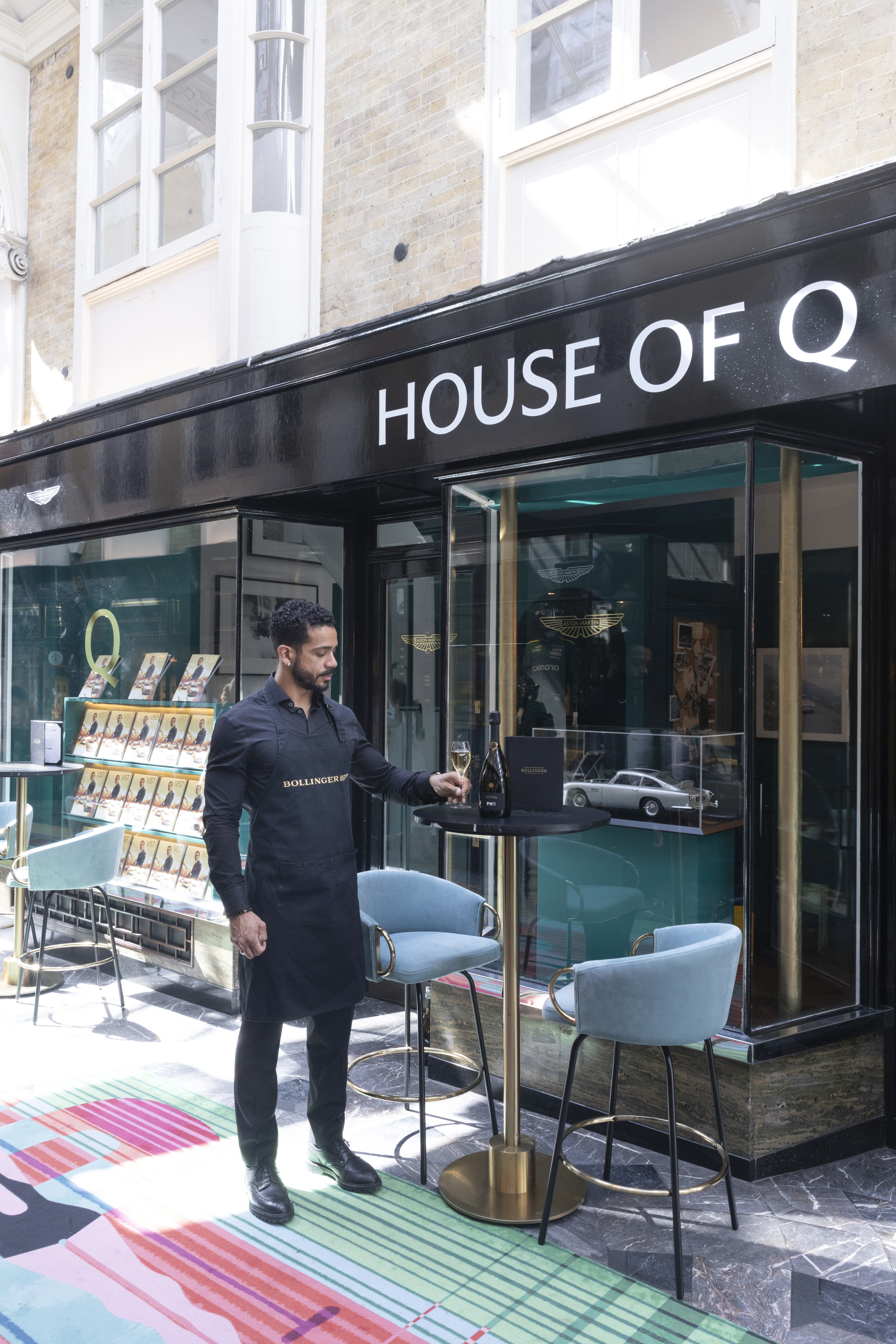 House of Q - a man standing outside the shop pouring champagne House of Q - a man standing outside the shop pouring champagne
