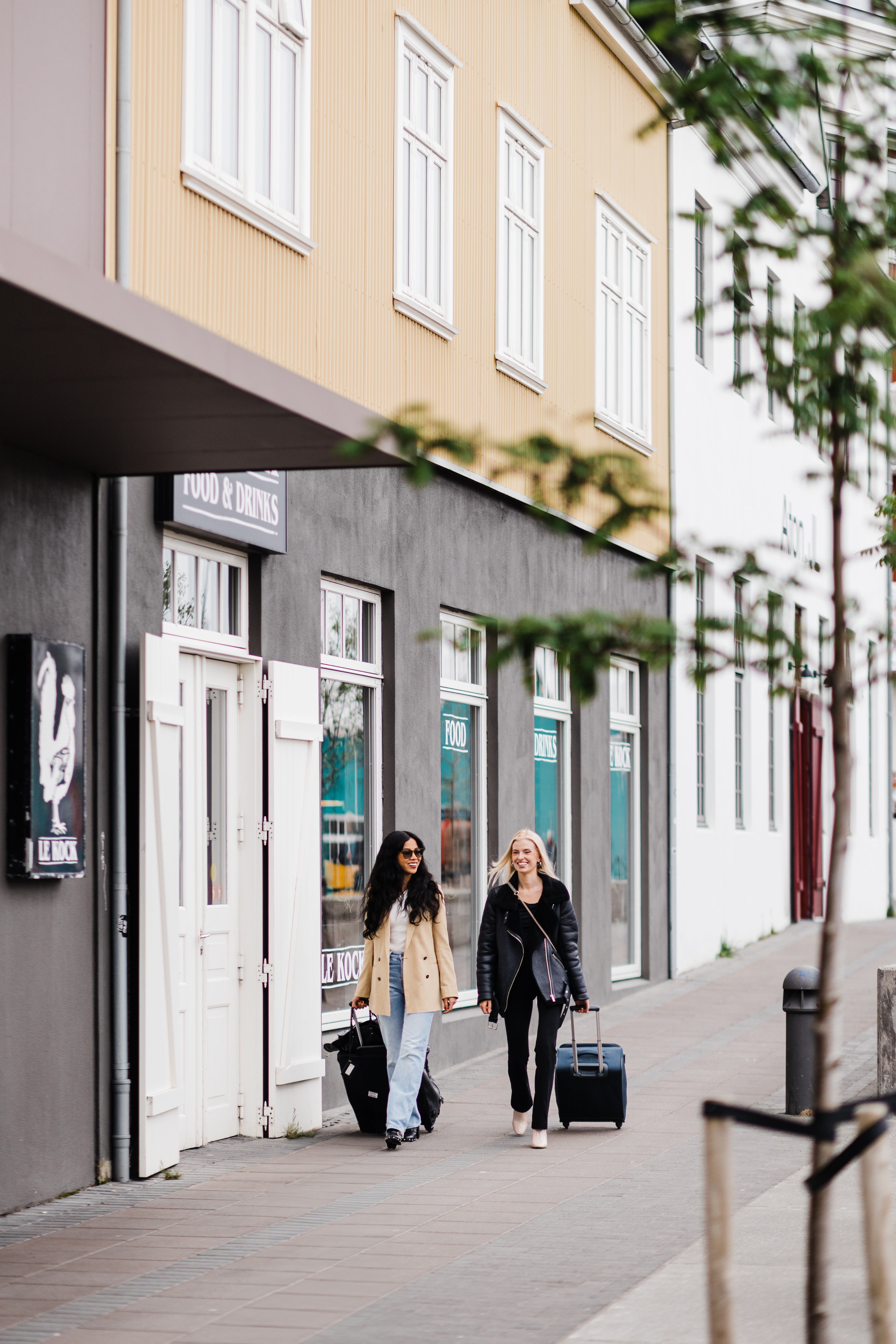 Hotel Exeter - road Hotel Exeter - two people walking with suitcases on a road next to a yellow building