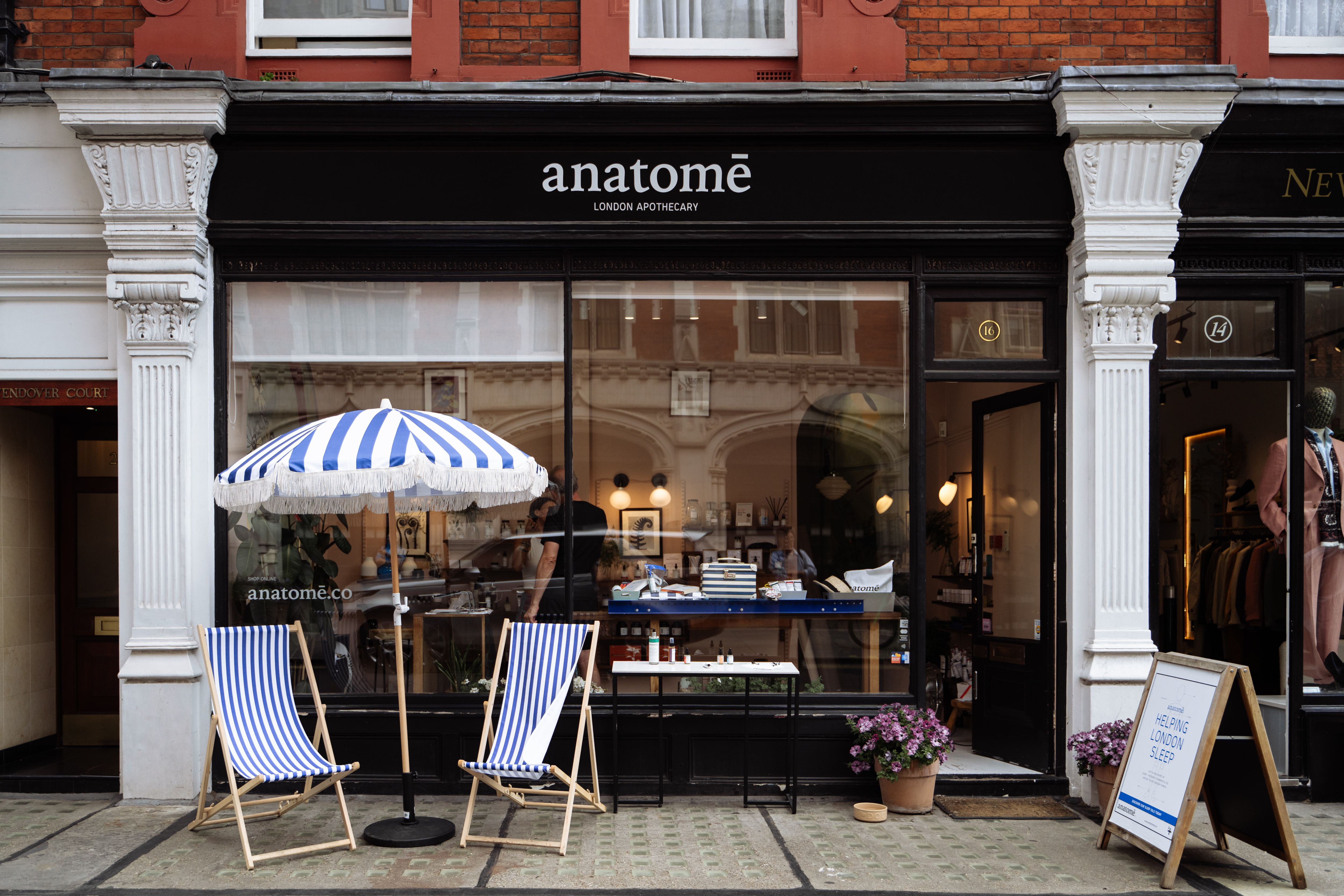 The shop front of anatomē on Chiltern Street featuring a striped blue and white beach umbrella with two deck chairs perfect for a 24 hour trip to Marylebone