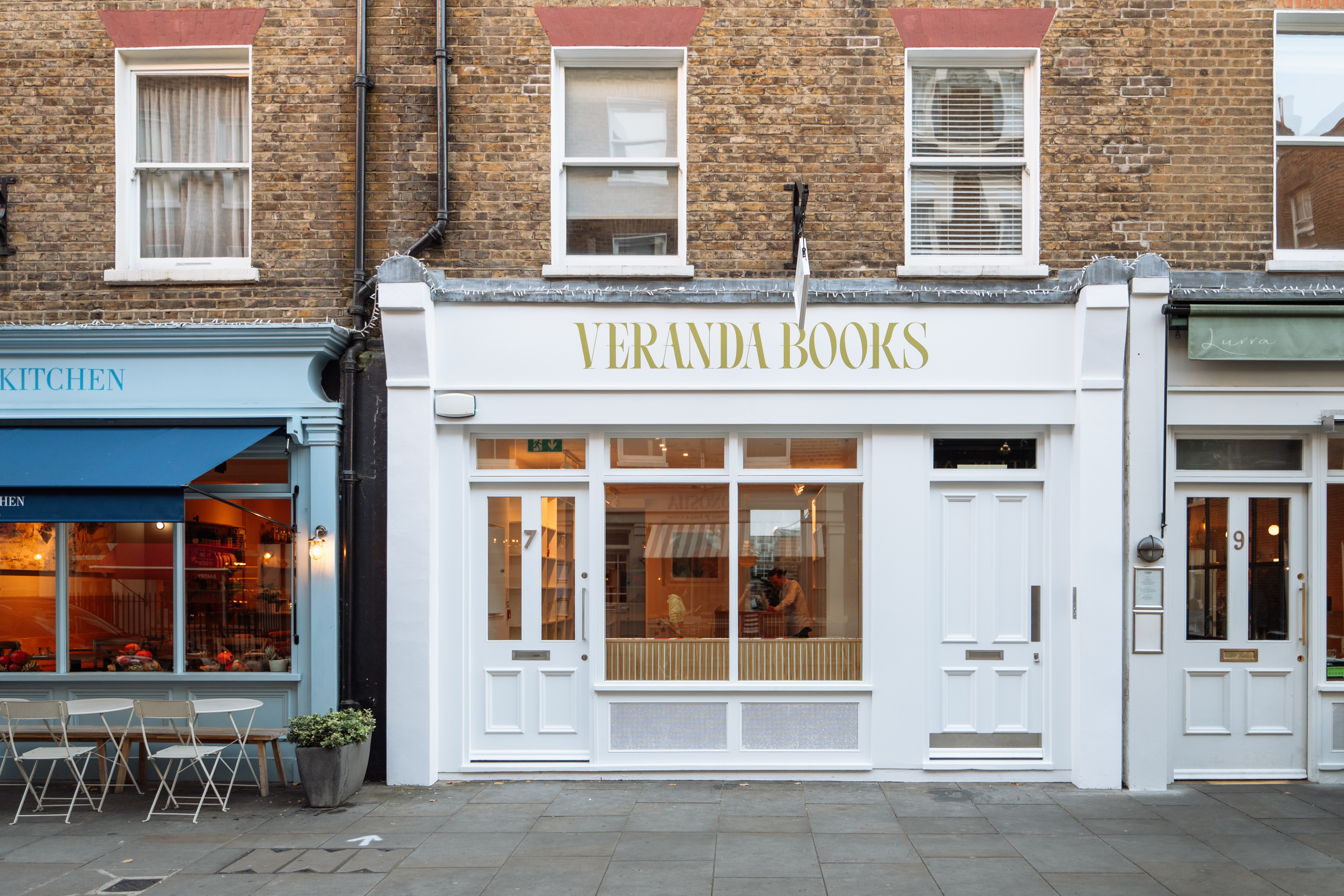 The storefront of Veranda Books next to a blue café called Kitchen, the perfect stop for your luxury 24 hours in Marylebone.