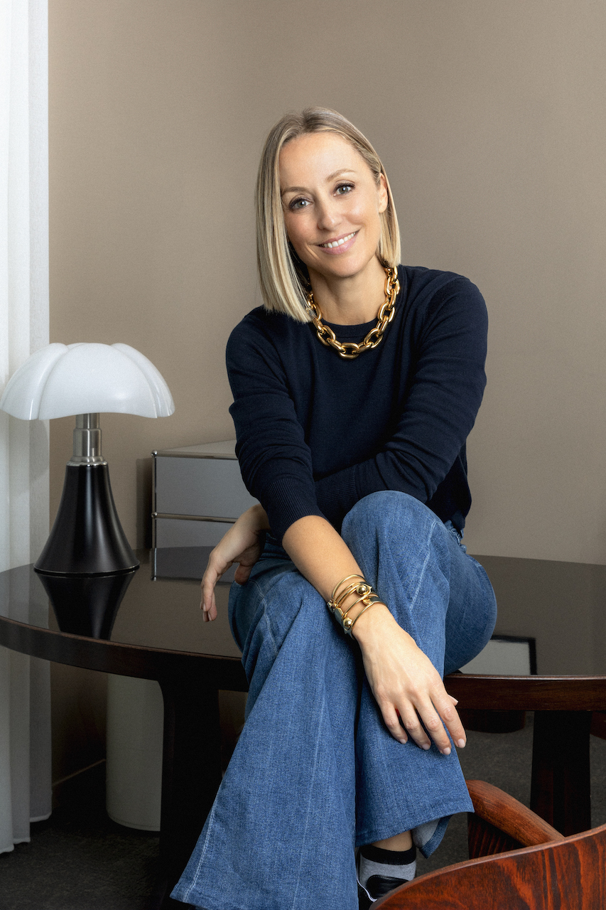SPHERE FT Business of Luxury Summit Barcelona - Fanny Moizant sat on a wooden table alongside a white lamp