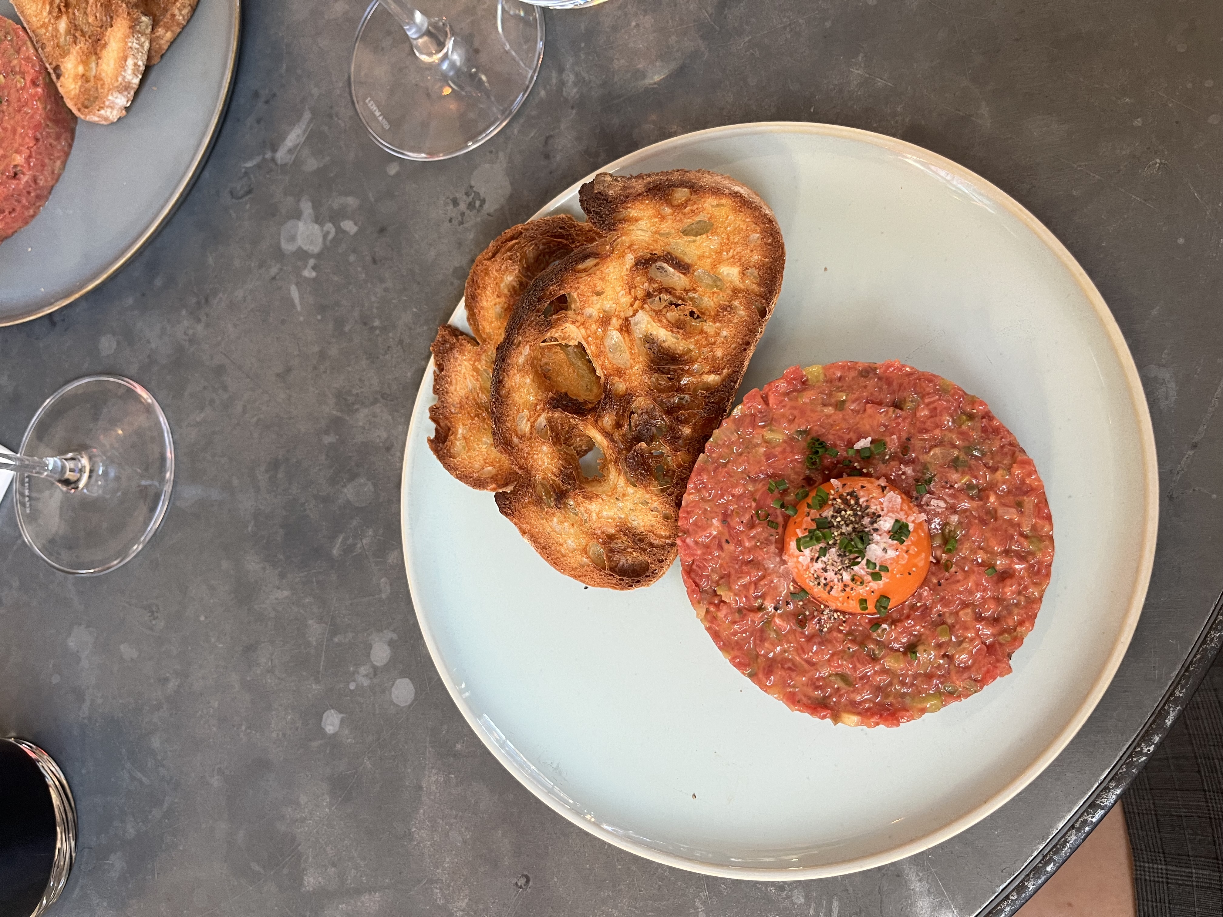 Luxury 24 Hours in Marylebone, a plate of steak tartare topped with an egg yolk and chives, served with toasted bread on the side.