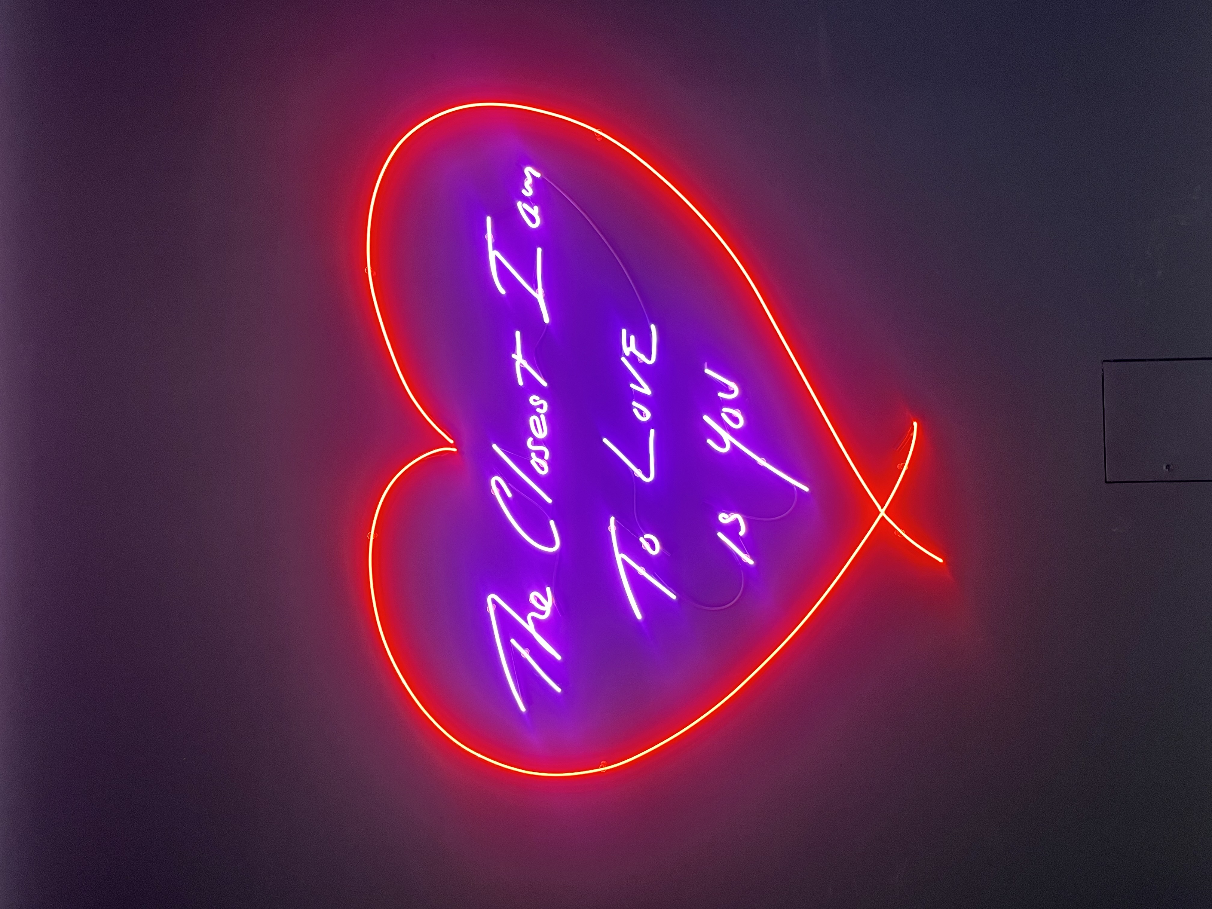 A neon sign in the shape of a heart with the text, The Closest I Am To Love Is You by Tracey Emin, found at the Moco Museum in Marylebone.