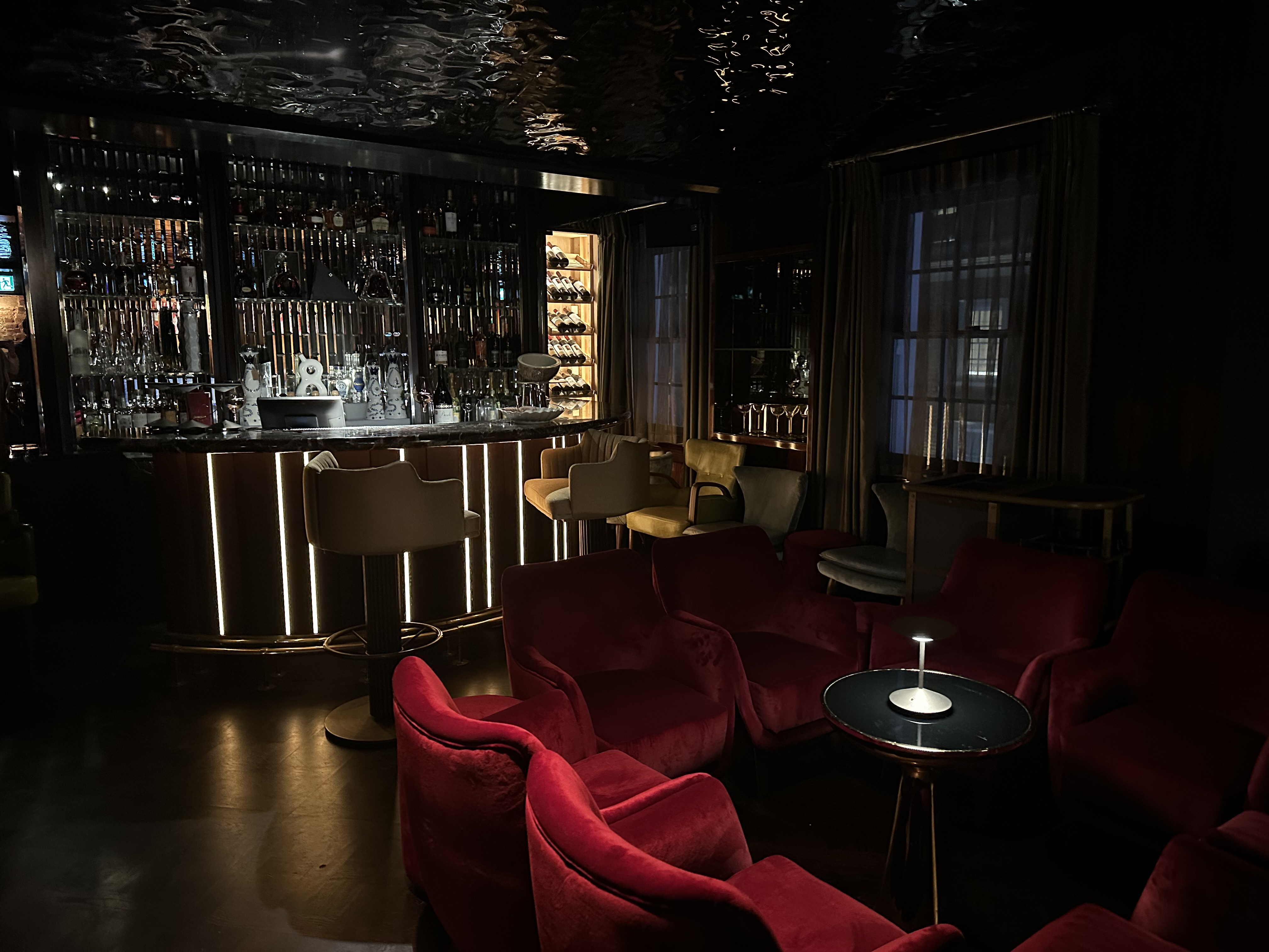 VATAVARAN - a low-lit bar with gold detailing and red velvet seating