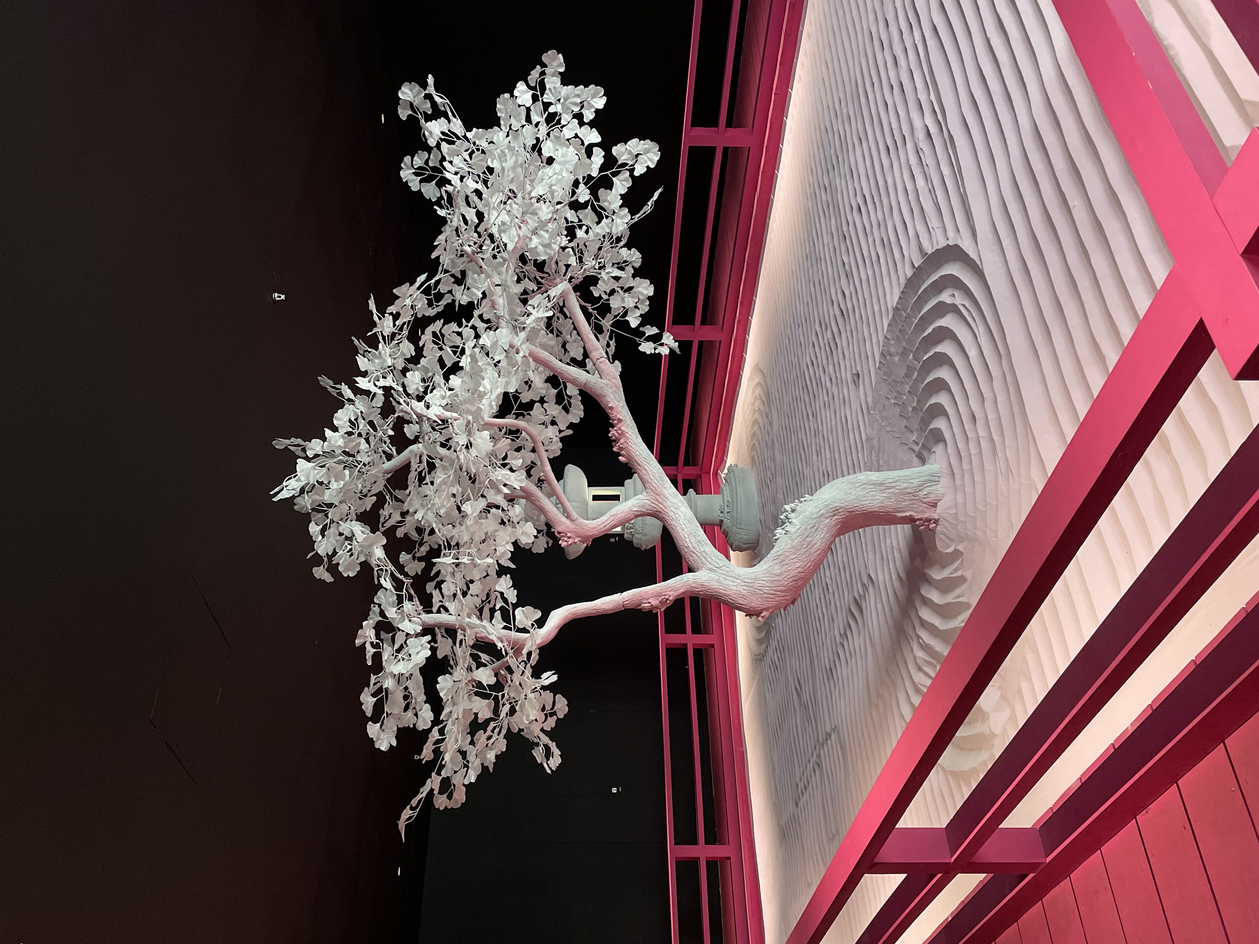 The Lunar Garden by Daniel Arsham featuring a white tree, placed in a sand-filled space, surrounded by a bright pink railing at the Moco Museum in Marylebone for your luxury 24 hour trip.