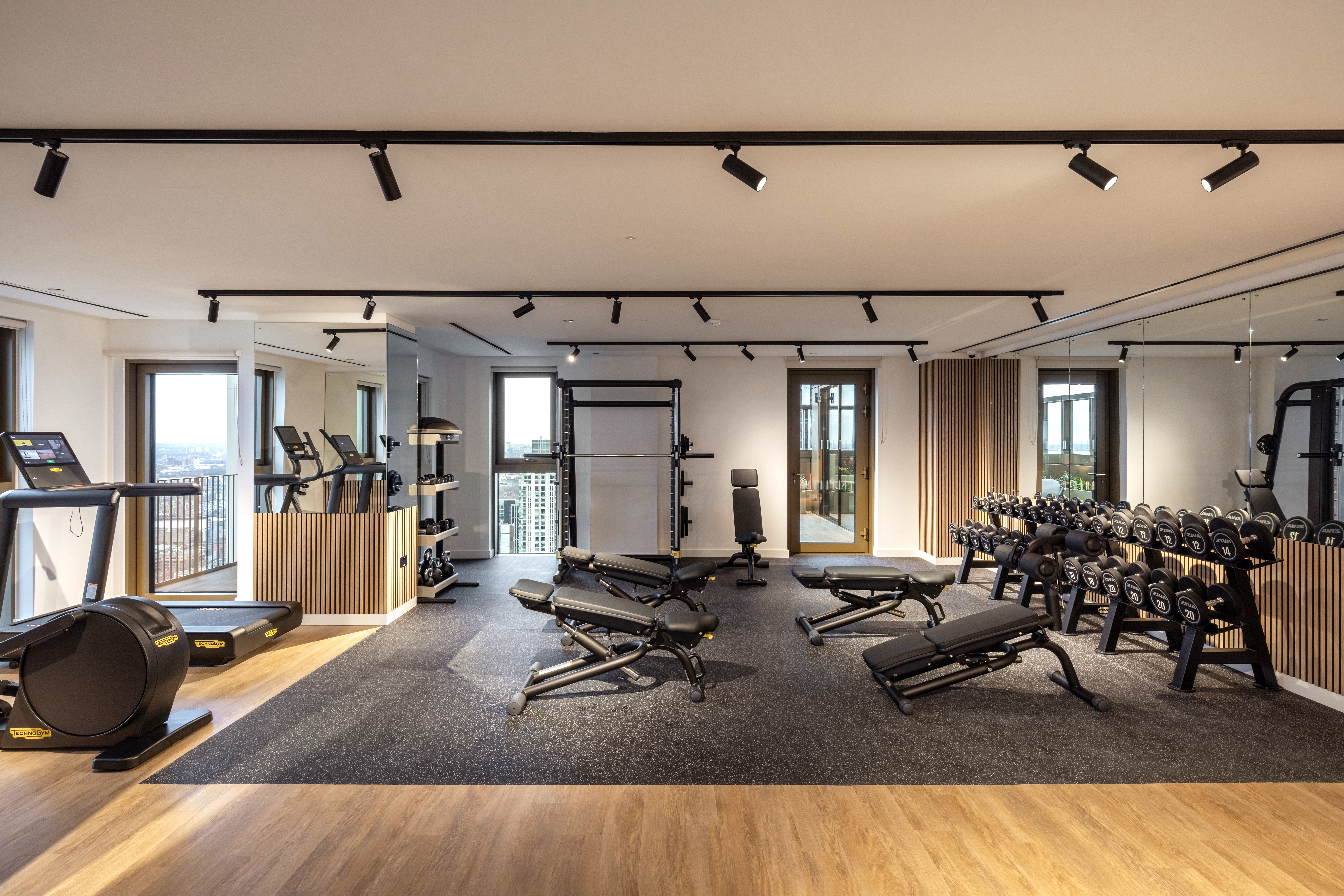 Property of the Week One Thames Quay - A state-of-the-art gym at One Thames Quay, featuring modern fitness equipment, including treadmills, free weights, adjustable benches, and strength-training machines. The gym is bright and spacious, with large windows offering stunning city views, sleek wooden accents, and mirrored walls enhancing the open feel of the space.