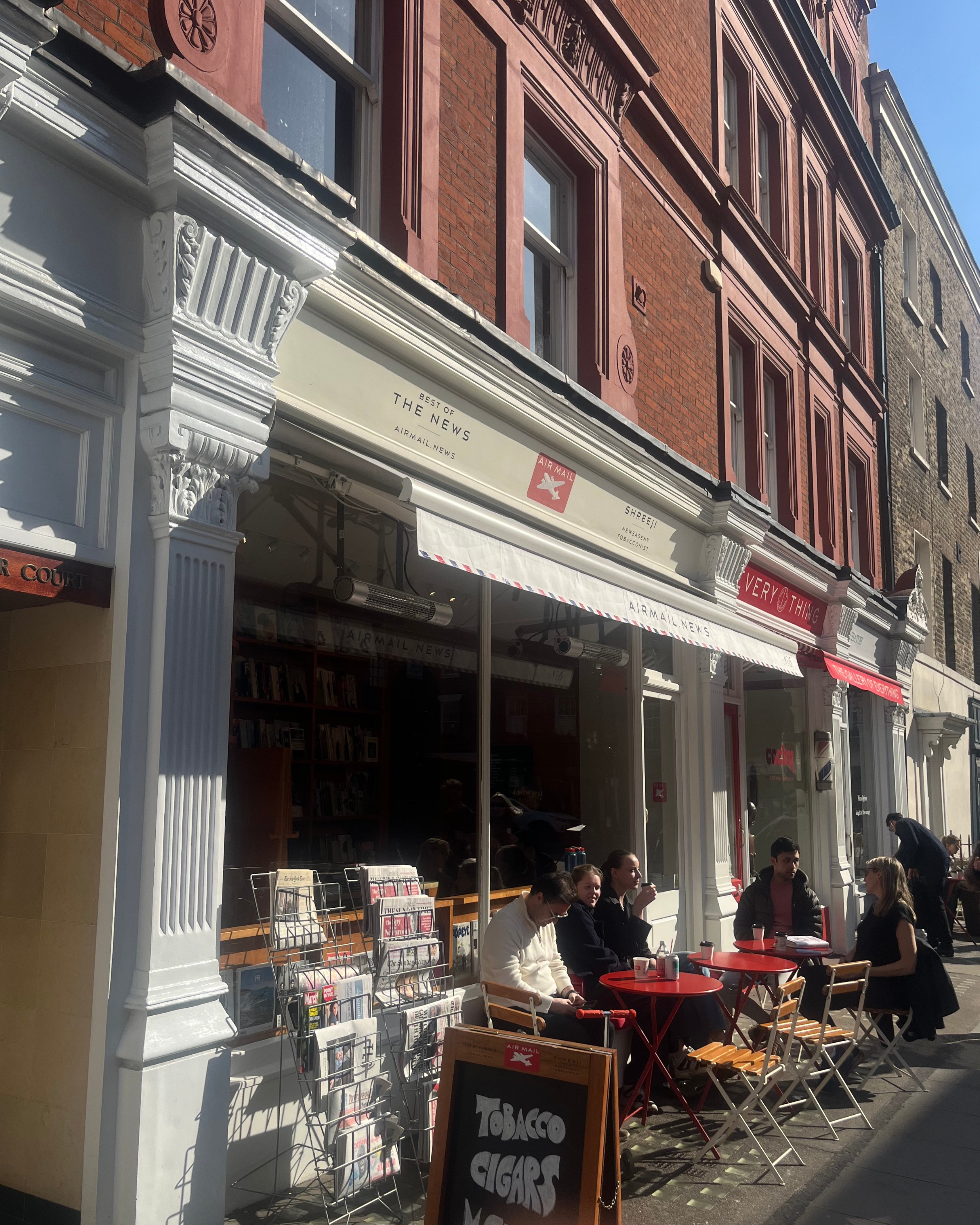 Shreeji Newsagents on Chiltern Street with on a sunny day, with racks of magazines out front.