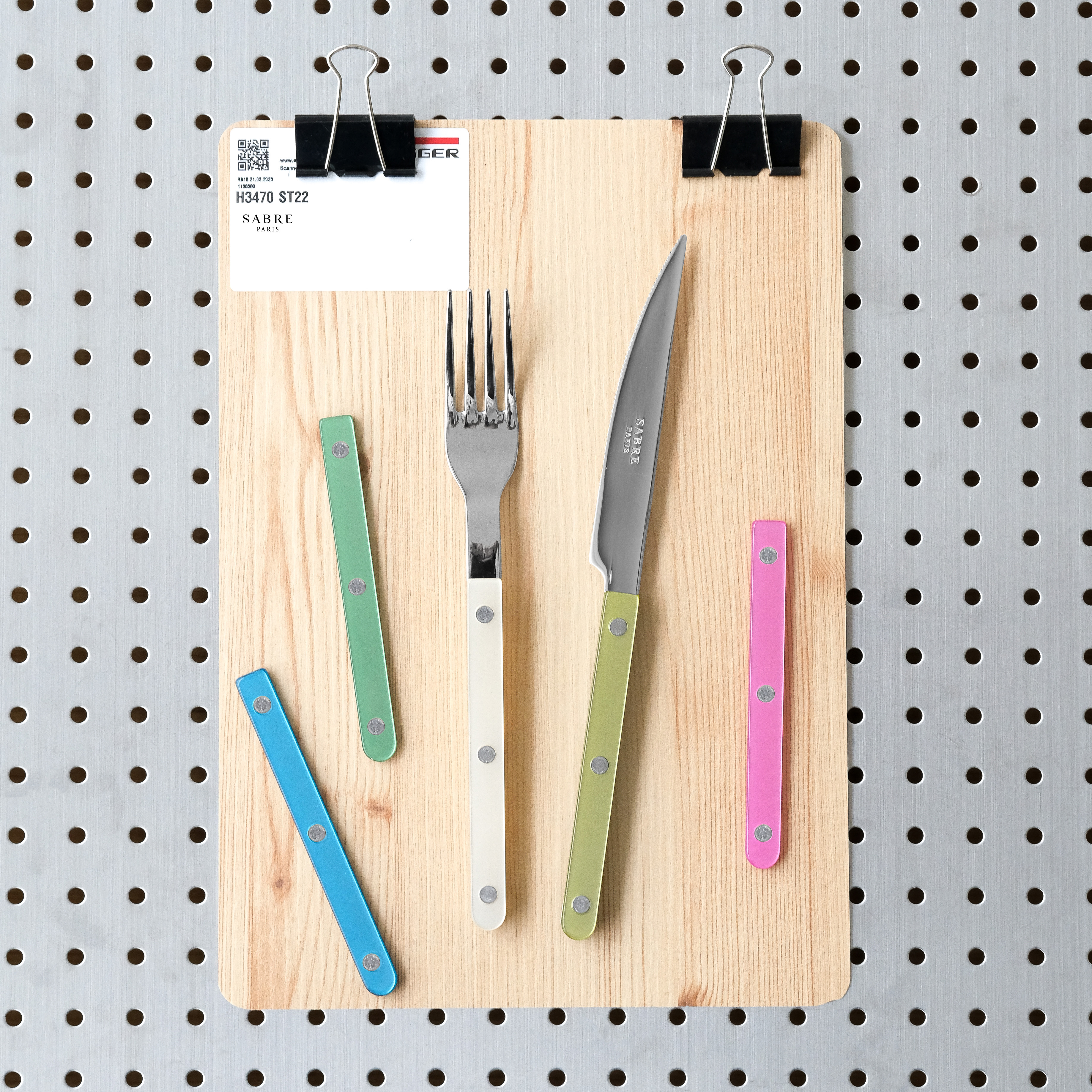 Luxury 24 Hours in Marylebone Sabre Paris fork and knife with various coloured handle options on a wooden board.