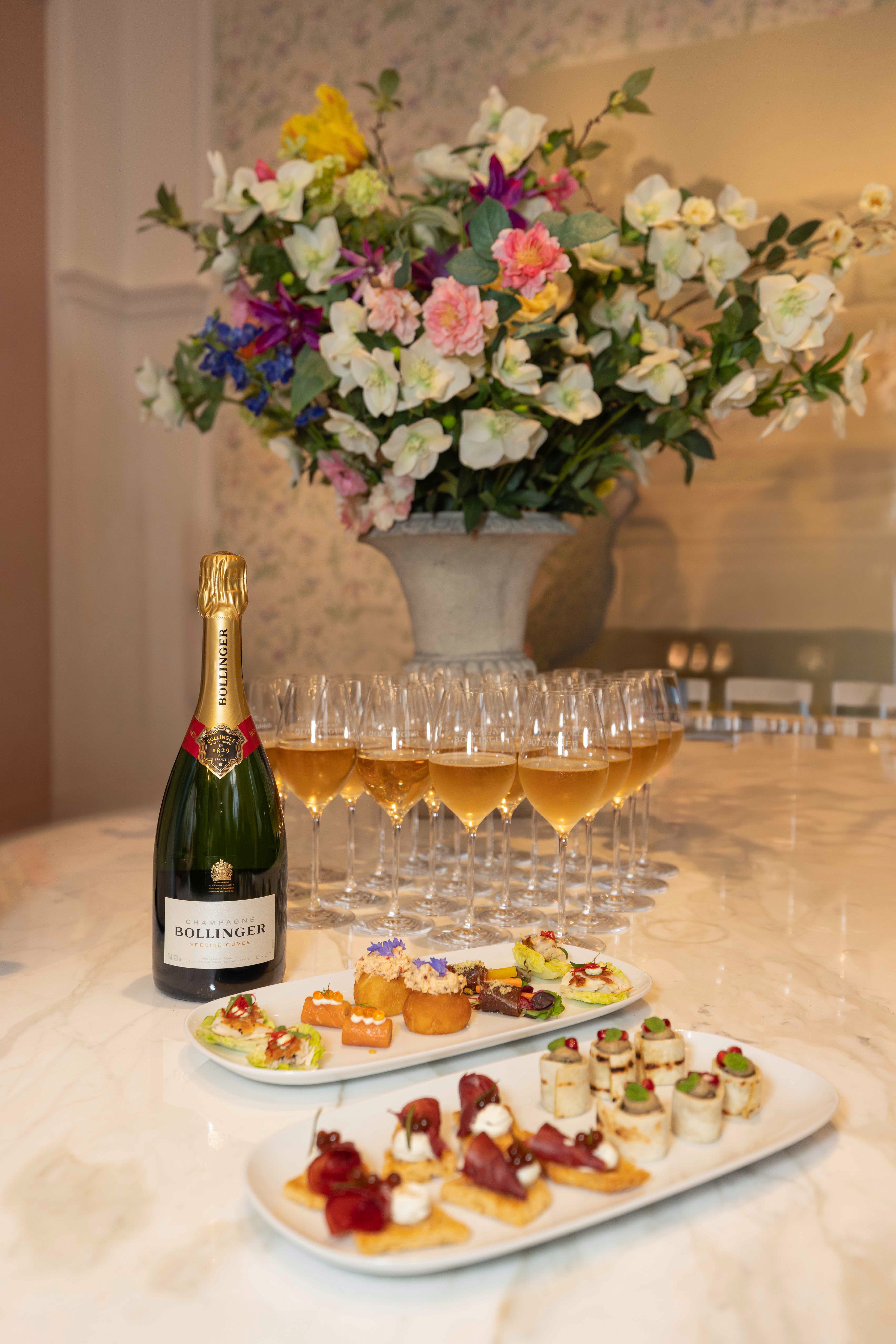 A bottle of Champagne Bollinger and plates of canapes served at the Cole & Son Salon discussing 'is craftsmanship worth it'.
