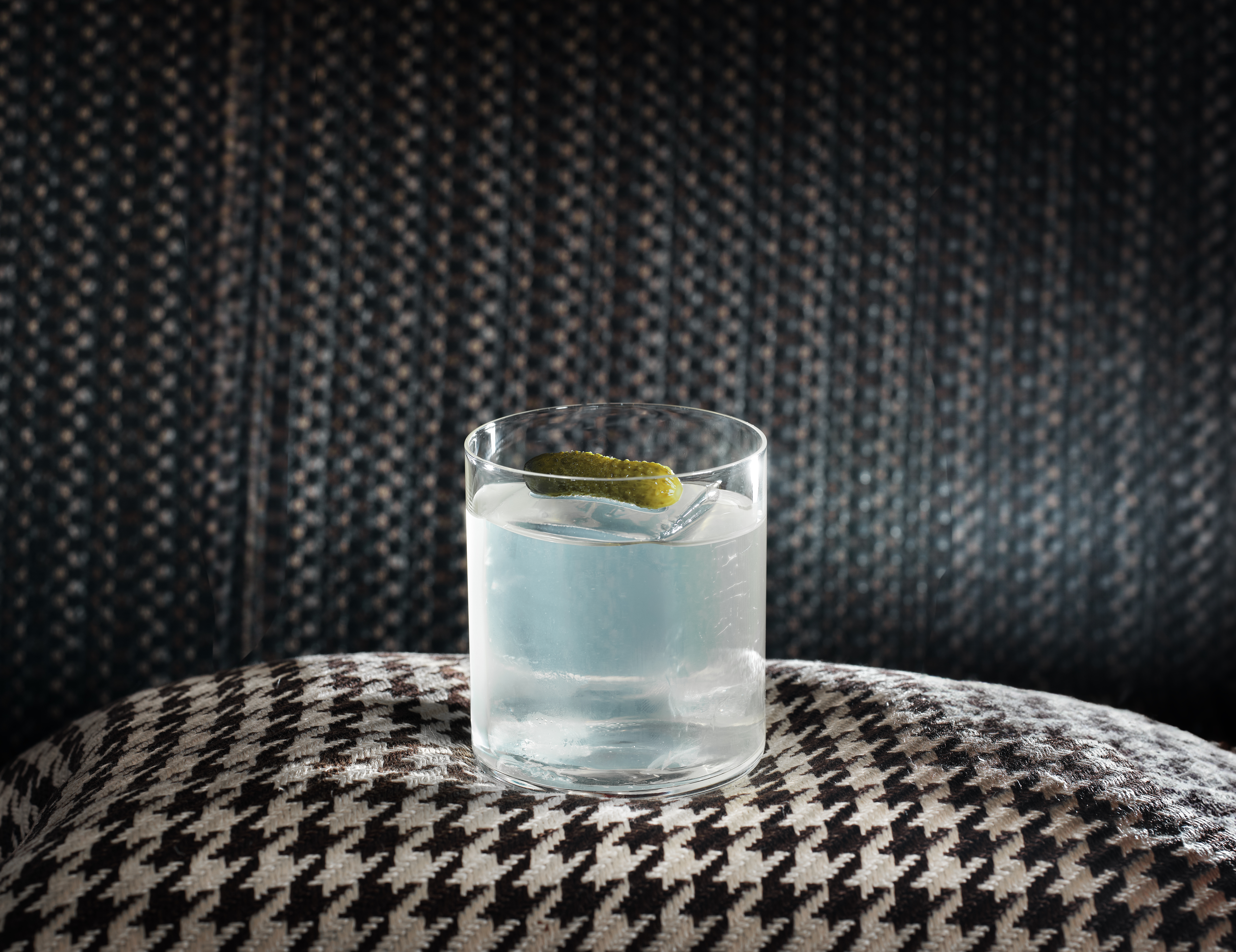 BAR45 Simplicity Cocktail -The Pick Me Up cocktail, garnished with a pickle and sat atop a houndstooth cushion.