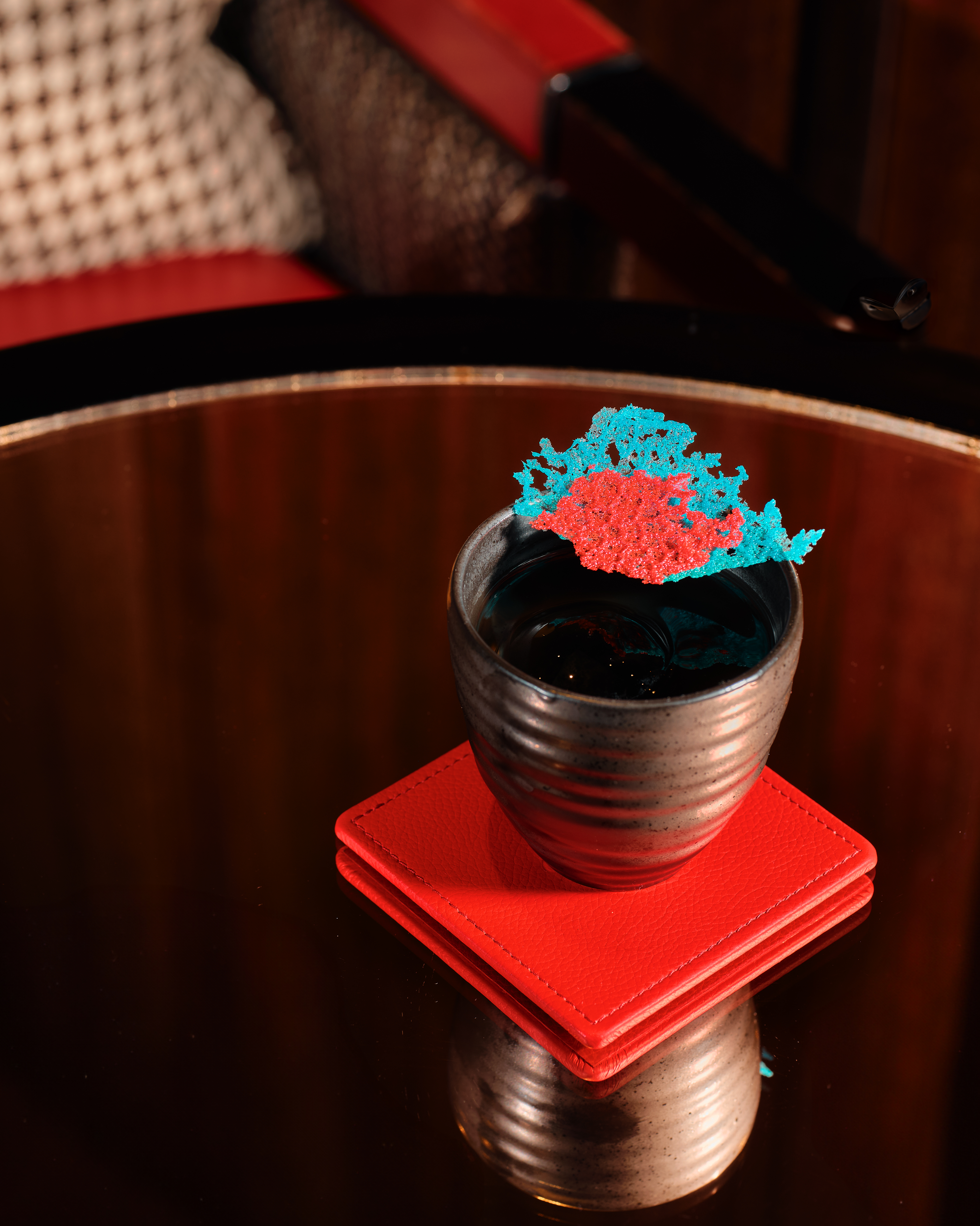 BAR45 Simplicity Cocktail - the Red & Blue with a colourful cracker, sat atop a red coaster.