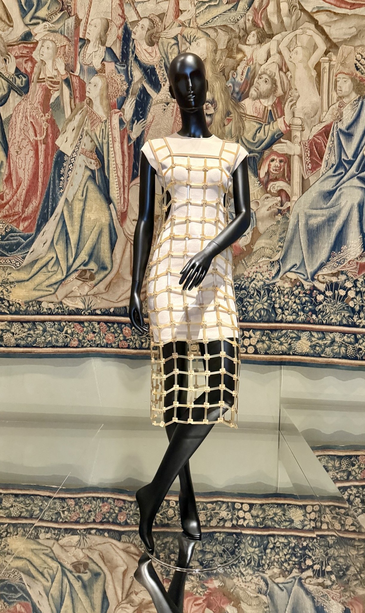 A mannequin dressed in a structured, grid-like dress by Hermes displayed at the Louvre Couture exhibition in Paris 2025.