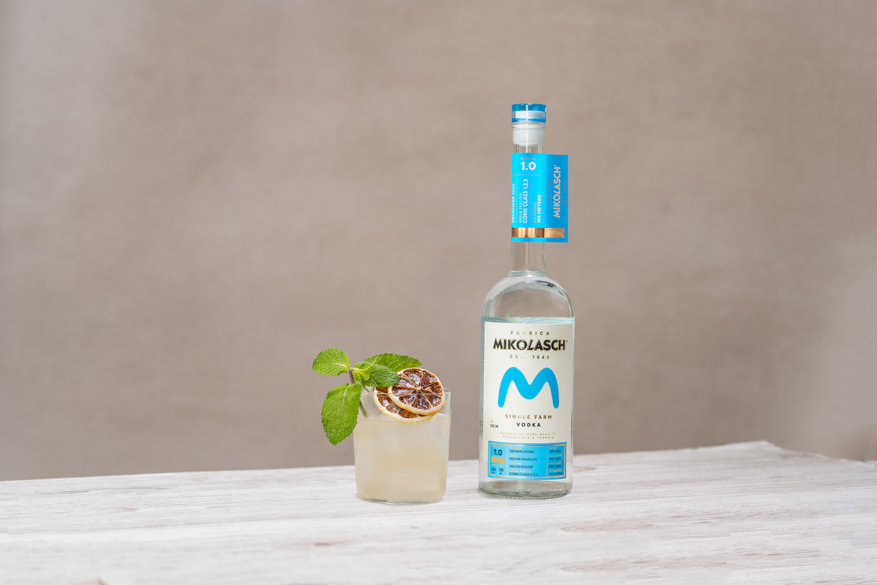 A orange-garnished cocktail using one of the sustainable spirits, Mikolasch, alongside a bottle of the vodka.