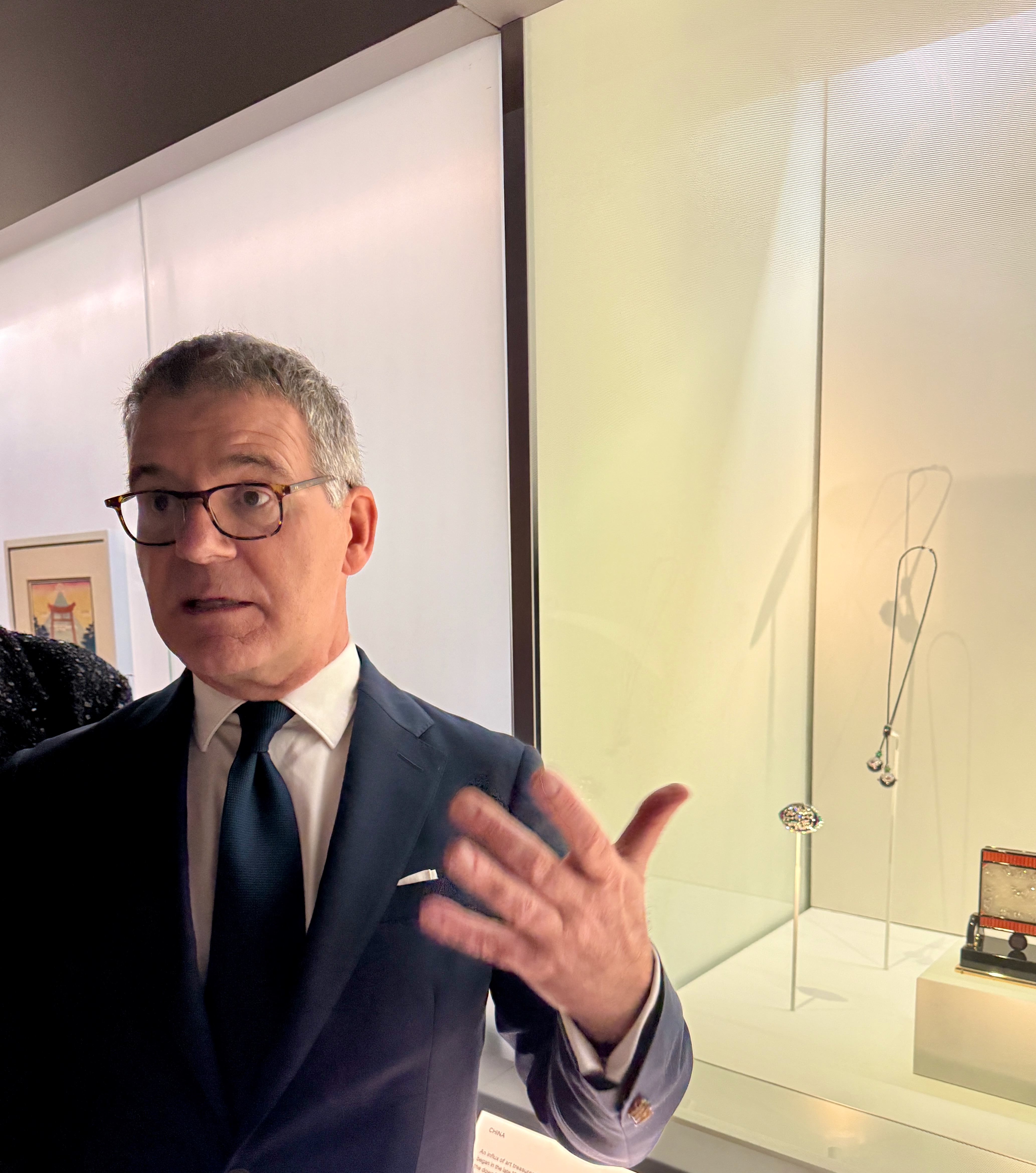 Pierre Rainero stood speaking in front of a jewellery display at the Cartier exhibition at the V&A.