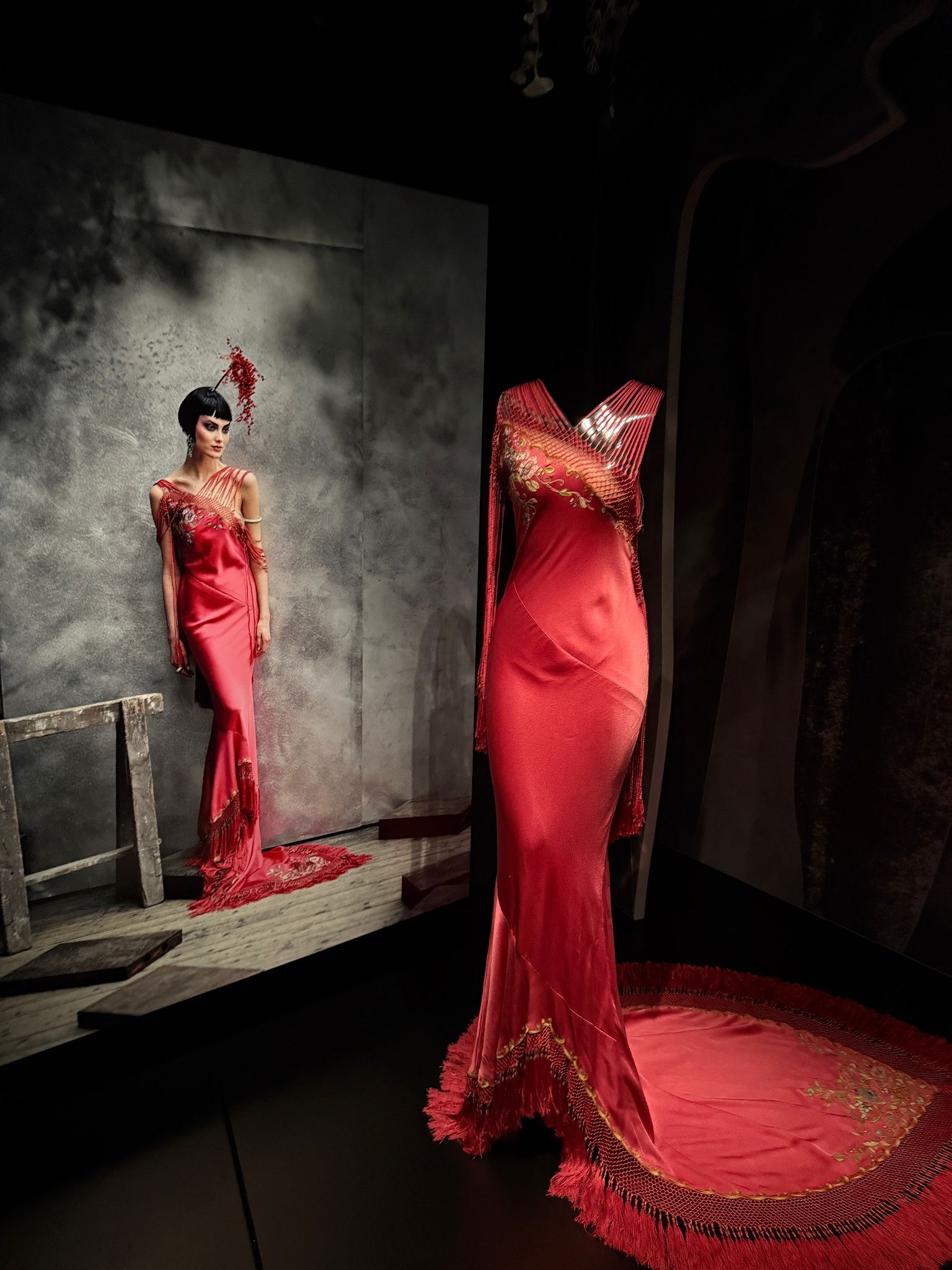 A red slinky Christian Dior dress displayed next to an image of a model wearing it at La Galerie Dior, a Paris archive exhibition, 2025.
