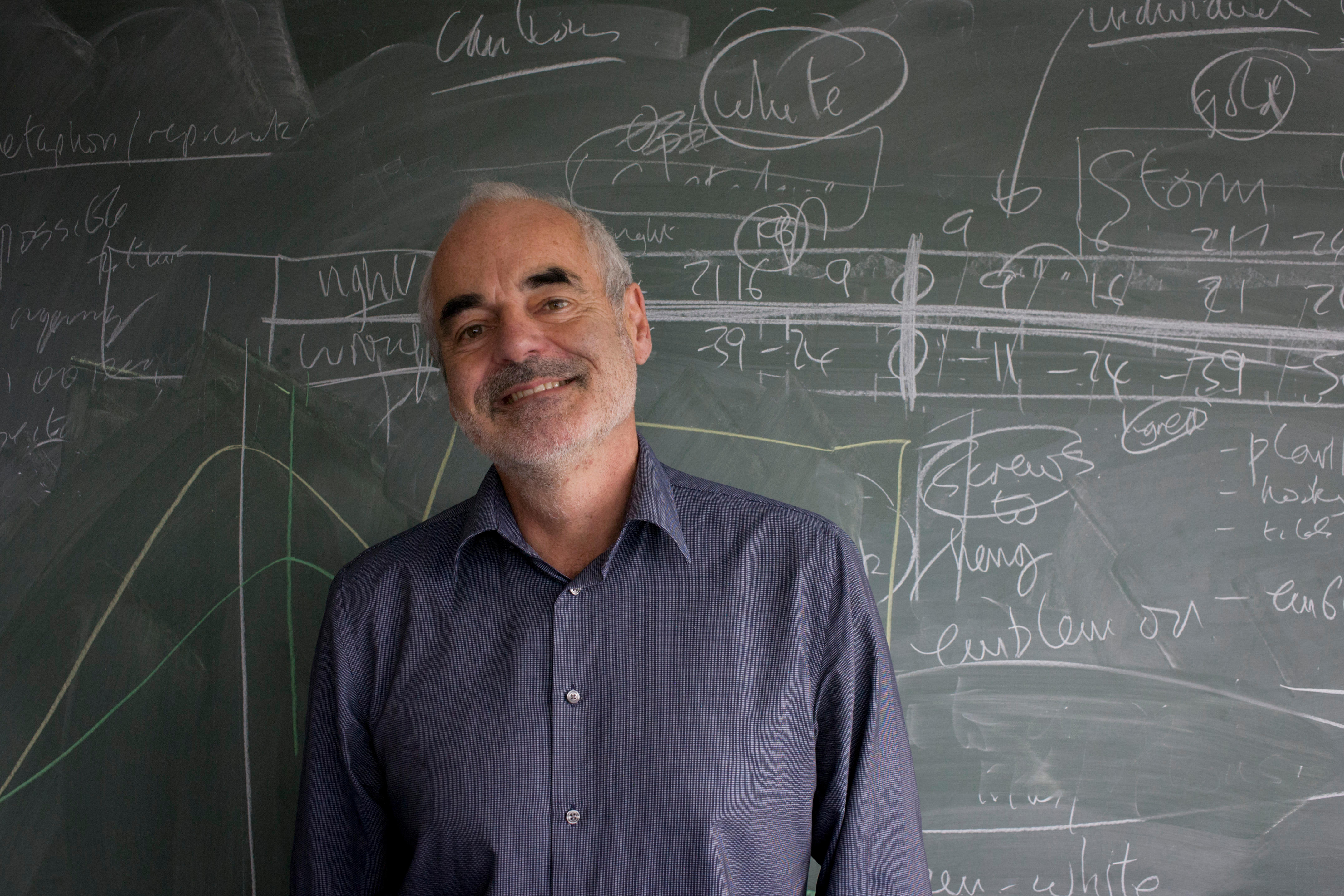 Sir David Spiegelhalter stood in front of a chalkboard of mathematics problems.