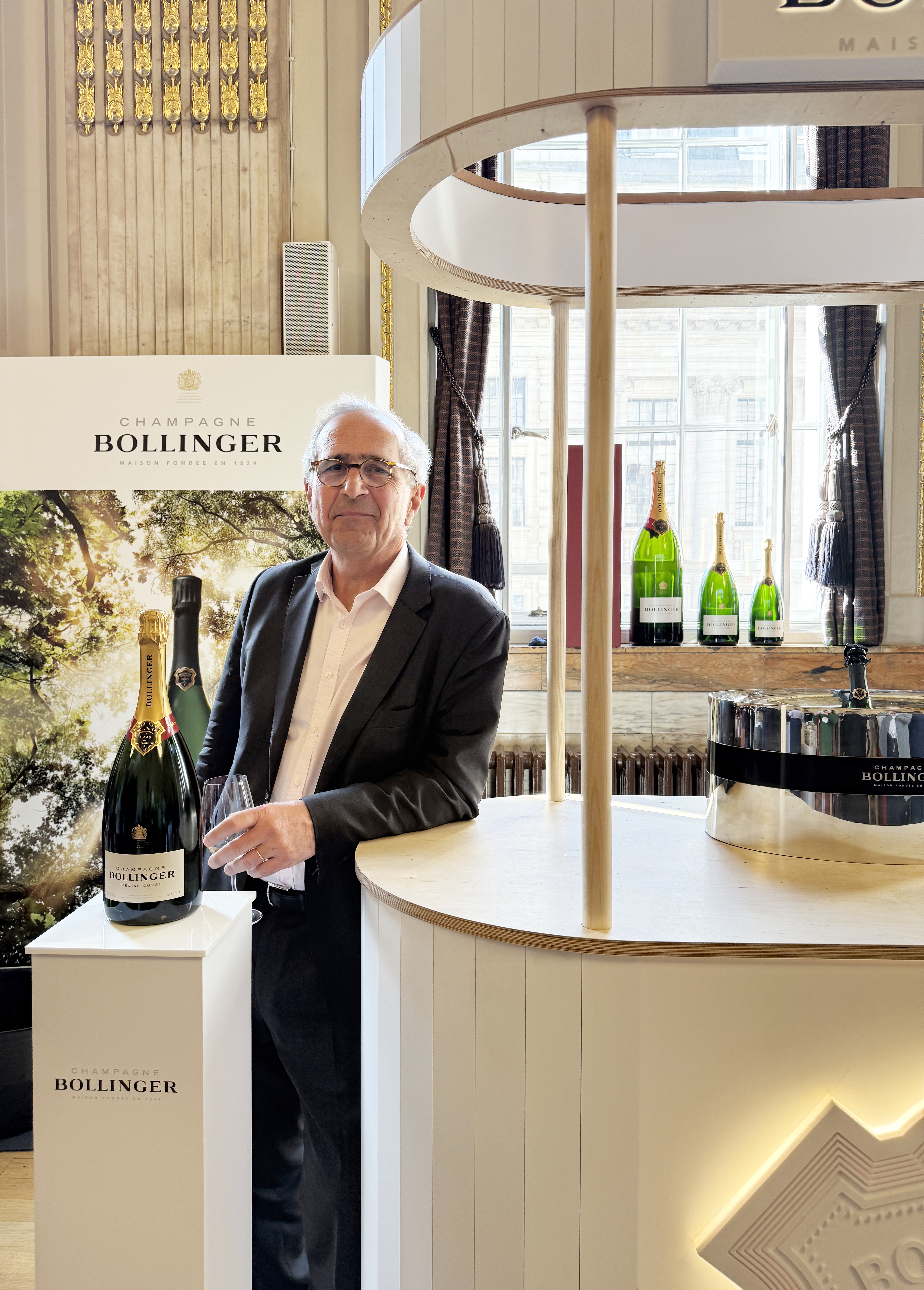 Étienne Bizot, stood alongside a bottle of Bollinger celebrating its 140-Year Royal Warrant.