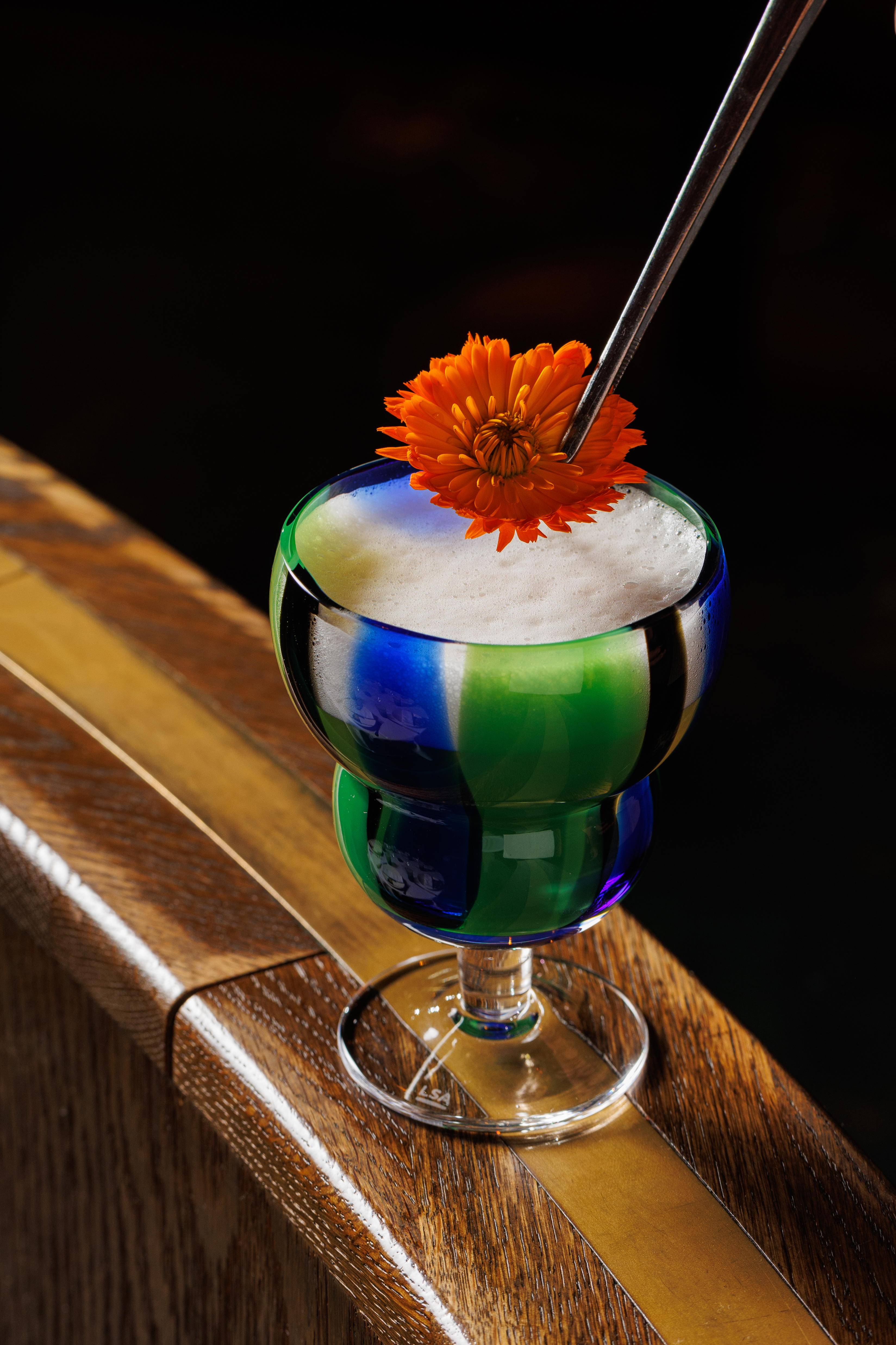 Amazonico Rainforest Cocktails - The Javari cocktail, green in colour and topped with an orange flower.