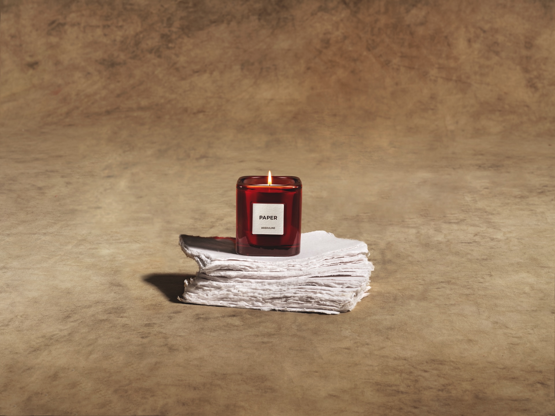 The paper candle photographed on layers of paper as part of The Library by Maison Assouline.