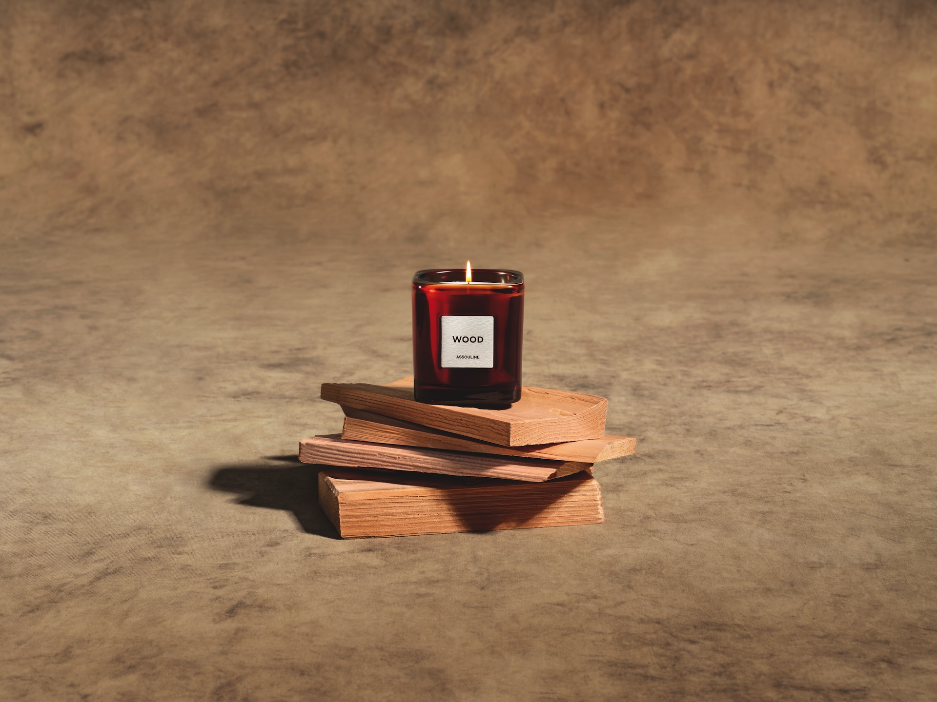 The wood candle photographed on slabs of wood as part of The Library by Maison Assouline.