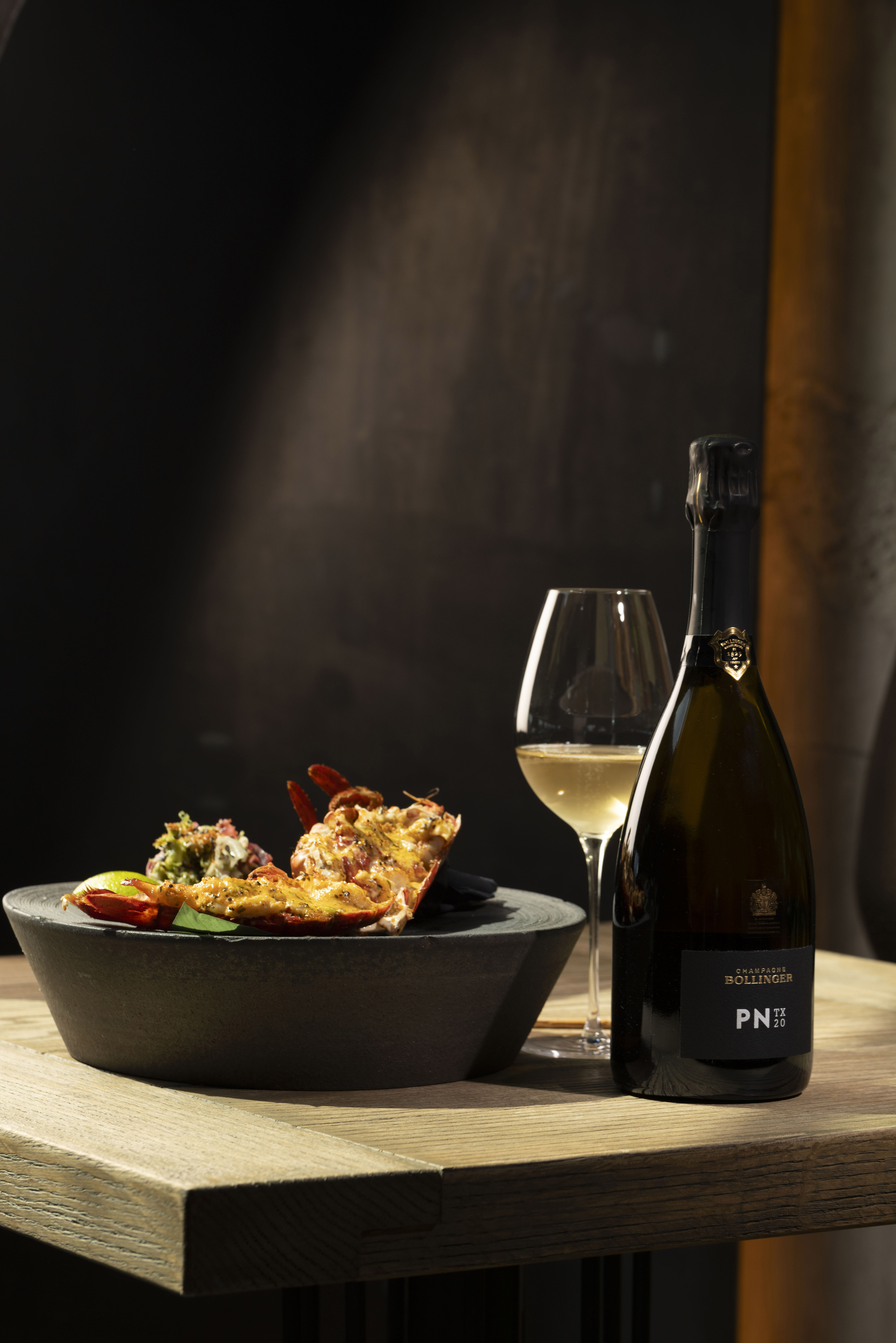 A bottle of PN TX20 sits beside a lobster dish for the launch of Bollinger PN TX20.