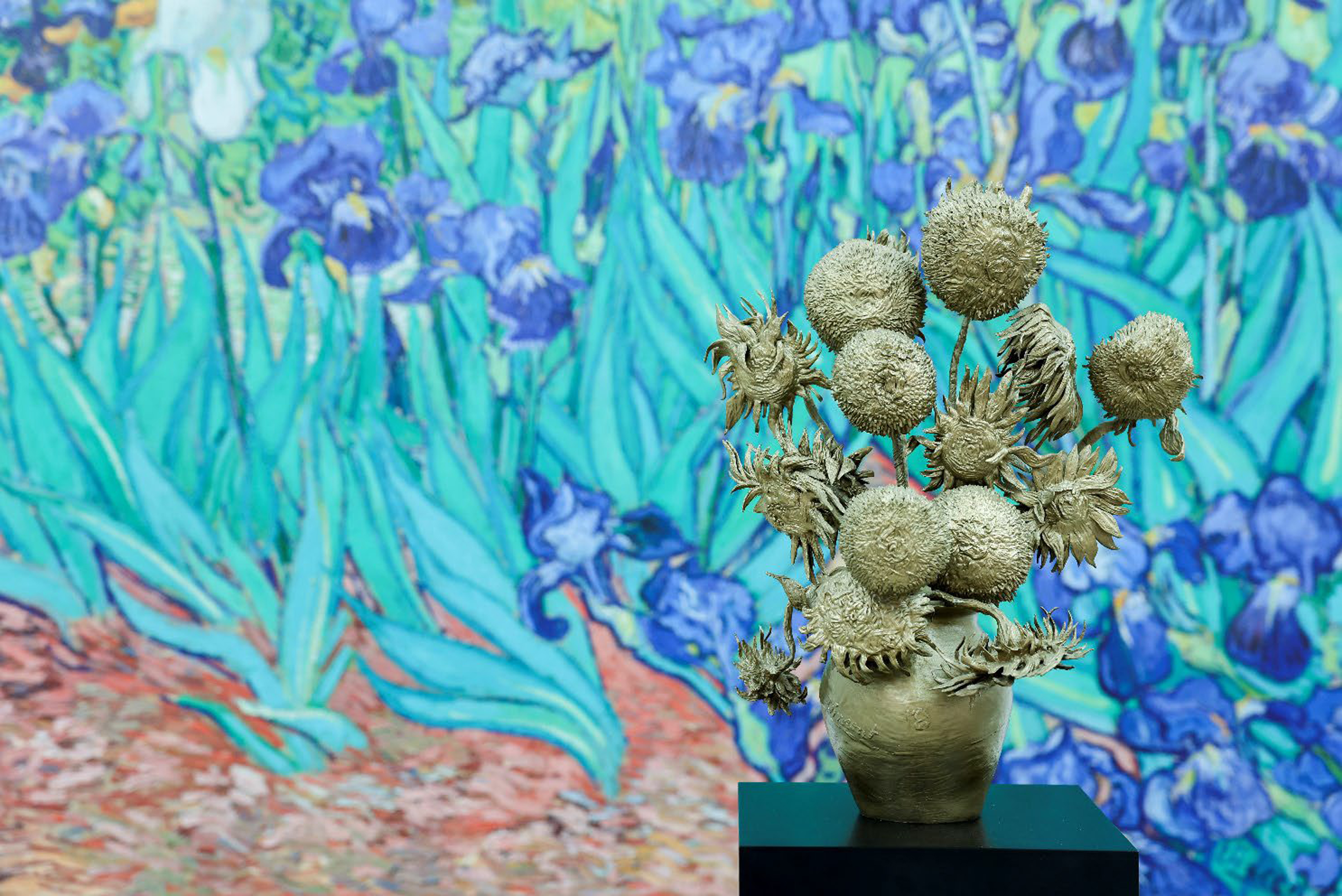 Vincent Van Gogh's vivid blue irises act as a backdrop to a sculpture of a vase of sunflowers, echoing another of his works.