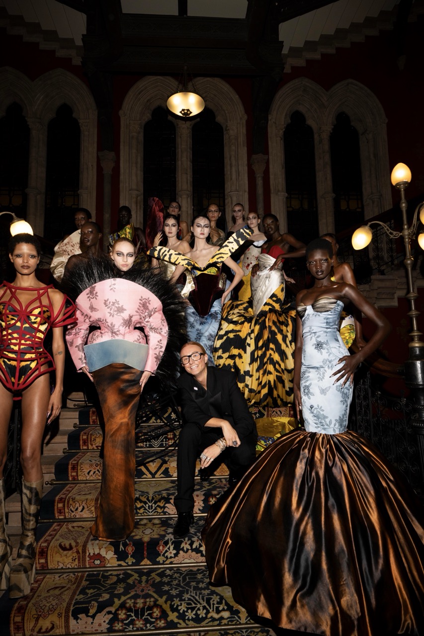 Designer Harris Reed flanked by models wearing his striking maximalist demi-couture creations.