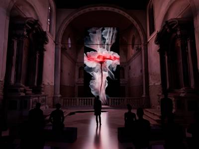 Walter Vanhaearents- a church lit up in red with a flower animation hanging at the alter and people watching  