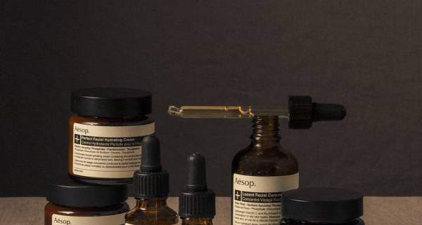 Aesop - brown bottles of skin and hair treatments with white labels and a pipette with product in it